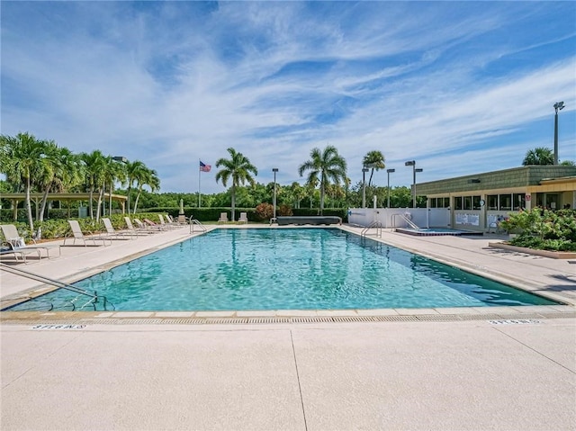 community pool with a patio area and fence