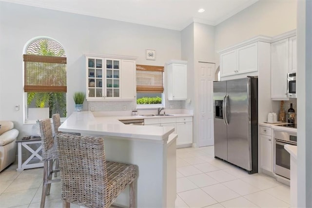 2214 Falls Cir, Vero Beach, FL 32967 - kitchen featuring a kitchen bar, sink, white cabinetry, appliances with stainless steel finishes, and kitchen peninsula
