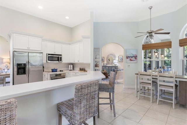 2214 Falls Cir, Vero Beach, FL 32967 - kitchen featuring white cabinetry, a kitchen breakfast bar, light tile patterned floors, kitchen peninsula, and stainless steel appliances
