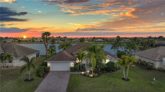 5688 Riverboat Cir SW, Vero Beach, FL 32968 - view of front of property featuring a water view, decorative driveway, a garage, a yard, and a residential view