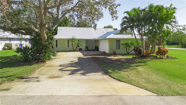 single story home with a garage, driveway, metal roof, and a front yard