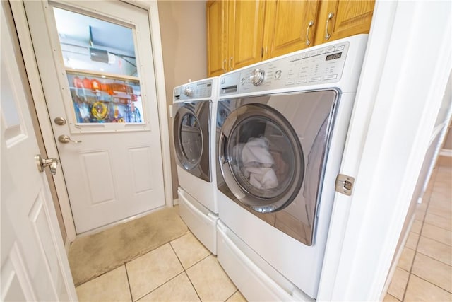 laundry room featuring cabinet space, light tile patterned floors, and washing machine and clothes dryer