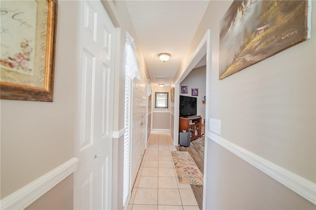 corridor featuring light tile patterned flooring and baseboards