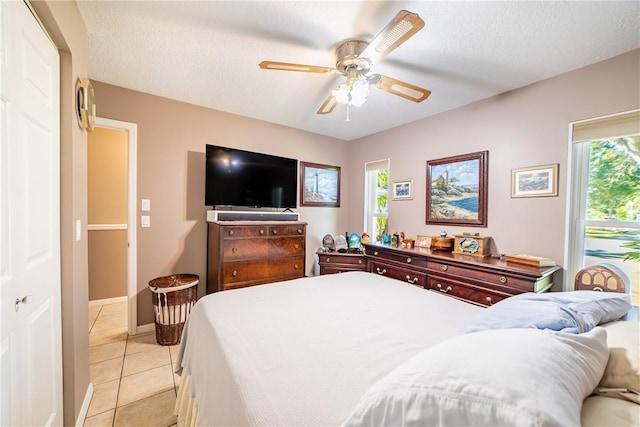 bedroom featuring light tile patterned floors, a textured ceiling, a ceiling fan, and baseboards