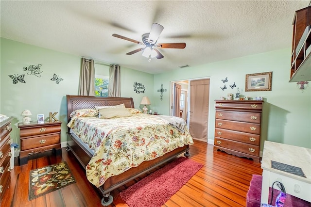 bedroom with visible vents, a ceiling fan, a textured ceiling, wood finished floors, and baseboards