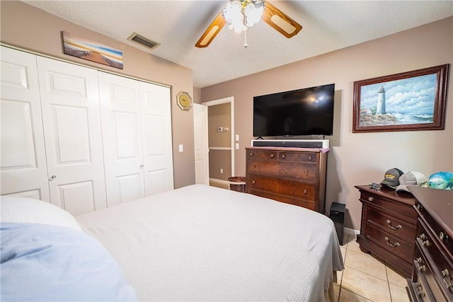 bedroom with light tile patterned floors, ceiling fan, visible vents, and a closet