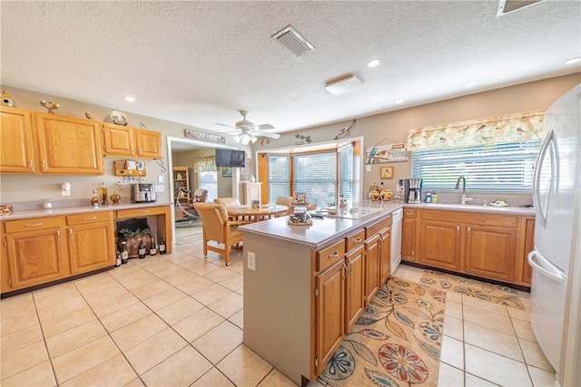 kitchen featuring light countertops, visible vents, light tile patterned flooring, a sink, and white appliances