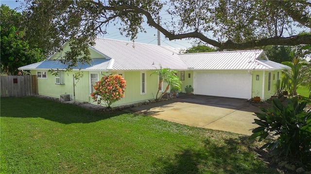 ranch-style home featuring metal roof, an attached garage, fence, driveway, and a front yard