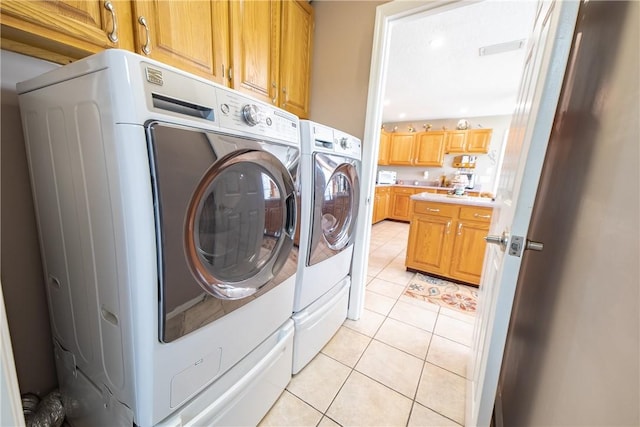 clothes washing area featuring visible vents, cabinet space, washer and clothes dryer, and light tile patterned floors