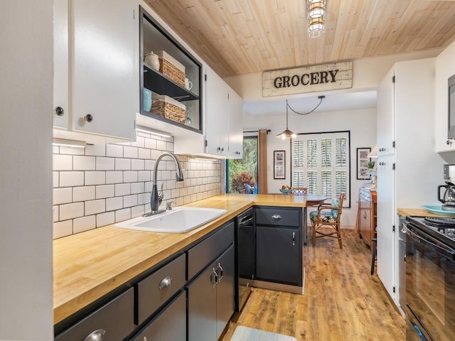 kitchen featuring electric range oven, a sink, white cabinetry, and pendant lighting