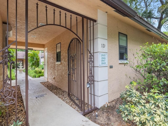 entrance to property featuring a gate and stucco siding