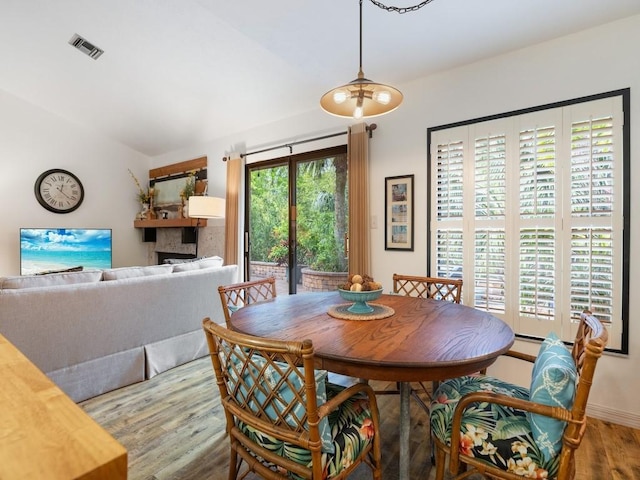 dining space with lofted ceiling, wood finished floors, and visible vents