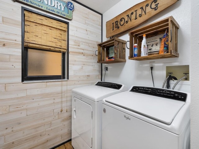 washroom featuring laundry area, separate washer and dryer, and wood walls