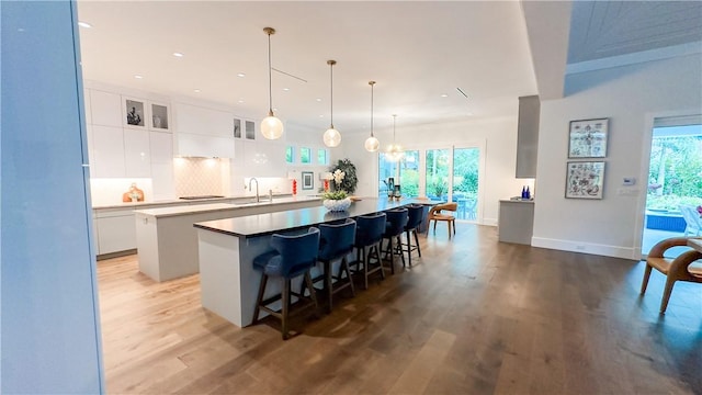 kitchen with white cabinetry, a kitchen bar, backsplash, pendant lighting, and a center island