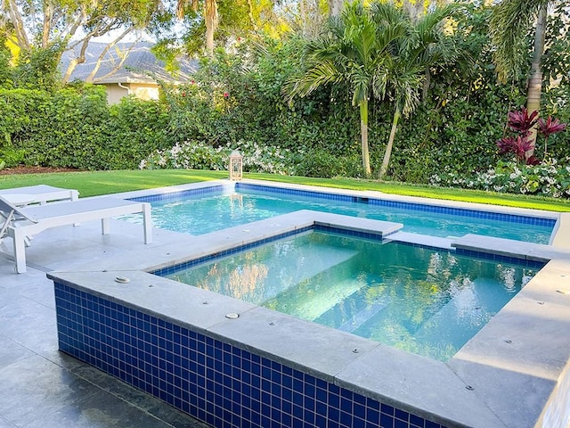 view of pool featuring an in ground hot tub, a lawn, and a patio