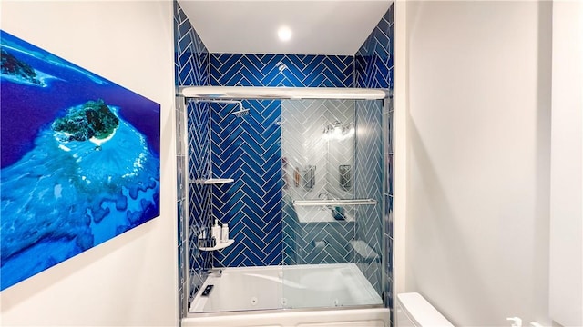 bathroom with toilet and bath / shower combo with glass door