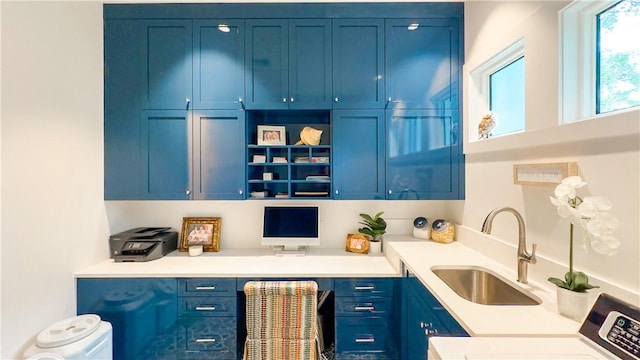 bar featuring washer / dryer, built in desk, blue cabinets, and sink