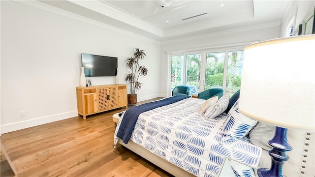 bedroom with a raised ceiling, crown molding, and hardwood / wood-style floors