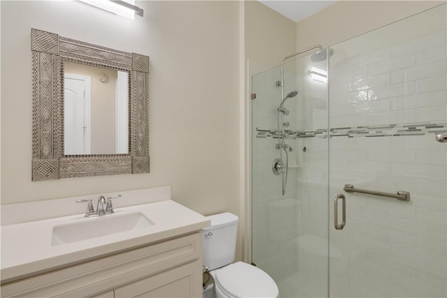 bathroom featuring toilet, a shower with door, and vanity