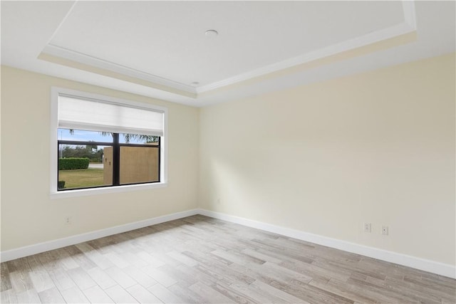 unfurnished room with a raised ceiling and light wood-type flooring