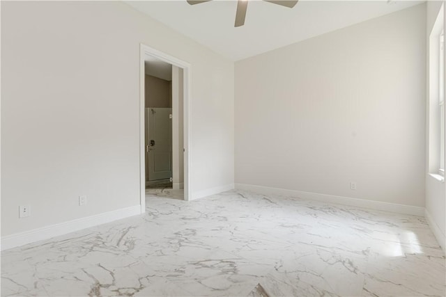 spare room with marble finish floor, baseboards, and a ceiling fan