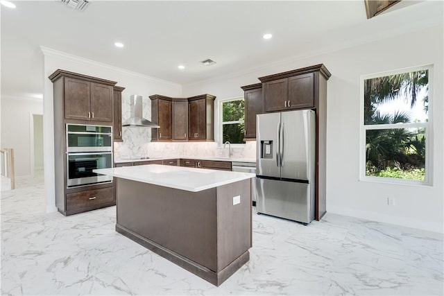 kitchen with a center island, marble finish floor, stainless steel appliances, light countertops, and wall chimney exhaust hood