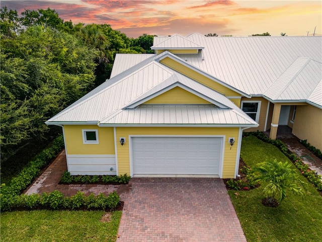 view of front of home with an attached garage, metal roof, and decorative driveway