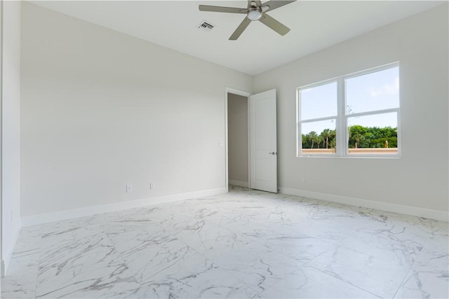 empty room featuring ceiling fan, marble finish floor, visible vents, and baseboards