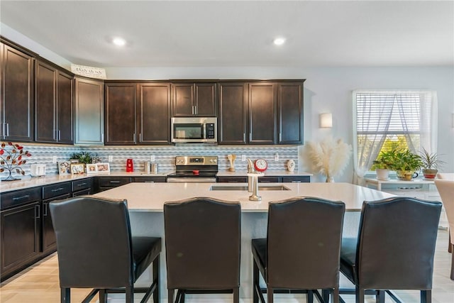 5990 Bearberry Dr, Vero Beach, FL 32967 - kitchen featuring appliances with stainless steel finishes, a kitchen island with sink, light countertops, backsplash, and recessed lighting
