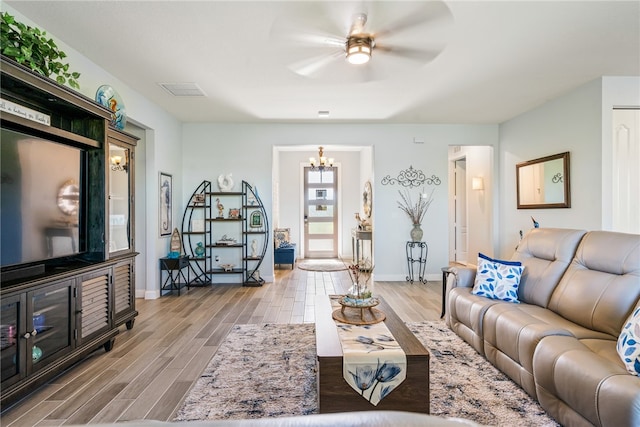 living room with ceiling fan with notable chandelier and light wood-type flooring