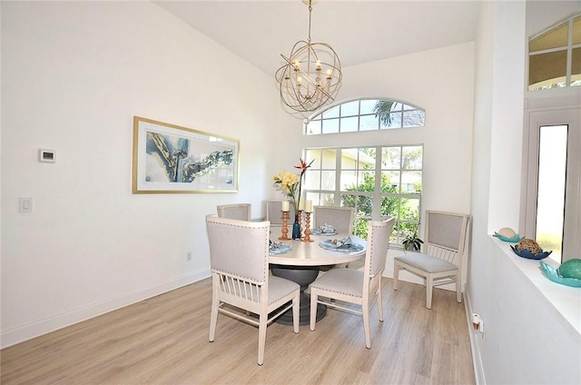 dining space with a chandelier, a high ceiling, and light wood-type flooring