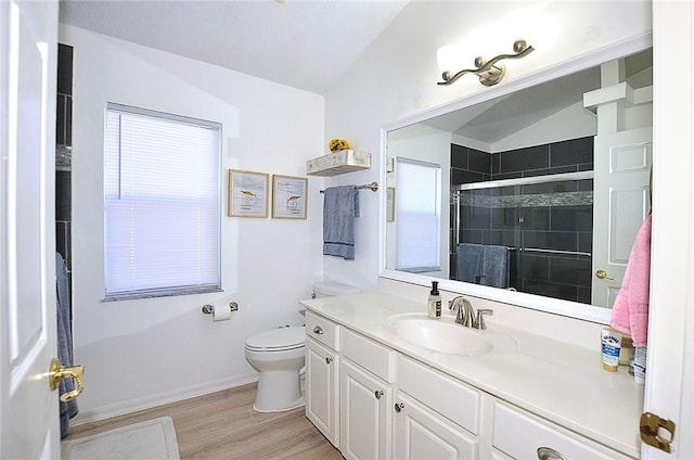 bathroom featuring vaulted ceiling, hardwood / wood-style flooring, vanity, an enclosed shower, and toilet