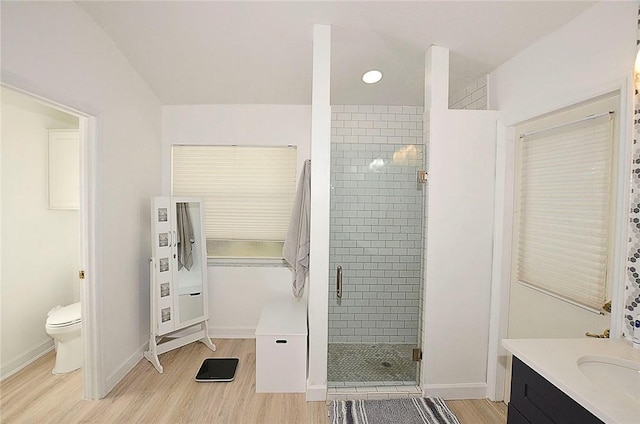 bathroom featuring wood-type flooring, toilet, vanity, and a shower with shower door