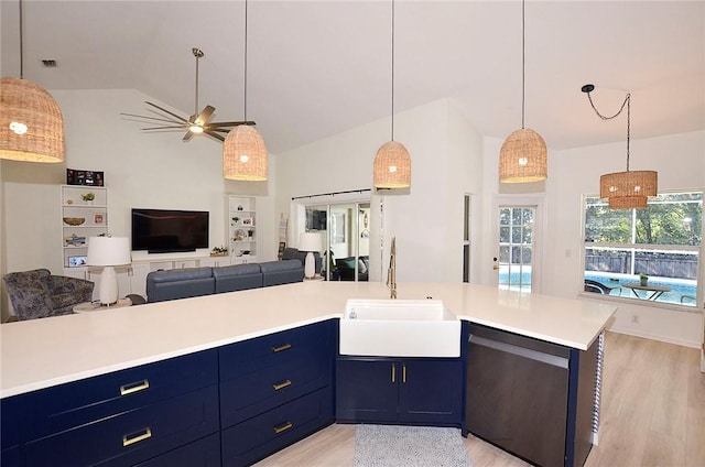 kitchen with dishwashing machine, sink, hanging light fixtures, light hardwood / wood-style floors, and blue cabinets