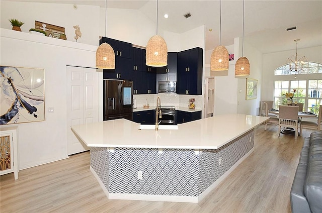 kitchen with pendant lighting, stainless steel appliances, a kitchen bar, and high vaulted ceiling