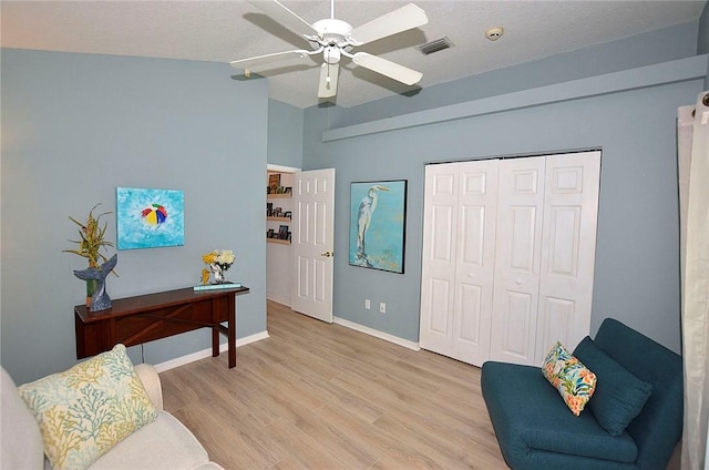 sitting room featuring a textured ceiling, vaulted ceiling, ceiling fan, and light wood-type flooring