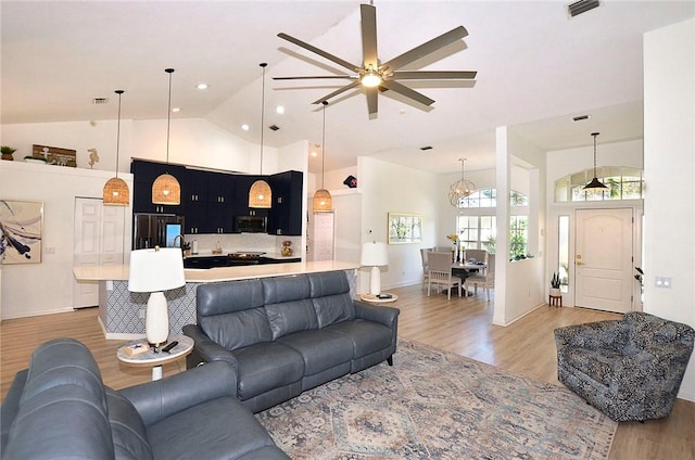 living room featuring wood-type flooring, high vaulted ceiling, and a chandelier