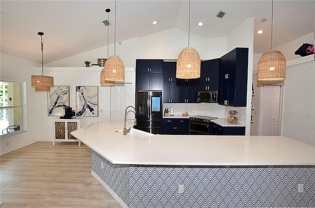 kitchen featuring hanging light fixtures, appliances with stainless steel finishes, sink, and a center island with sink