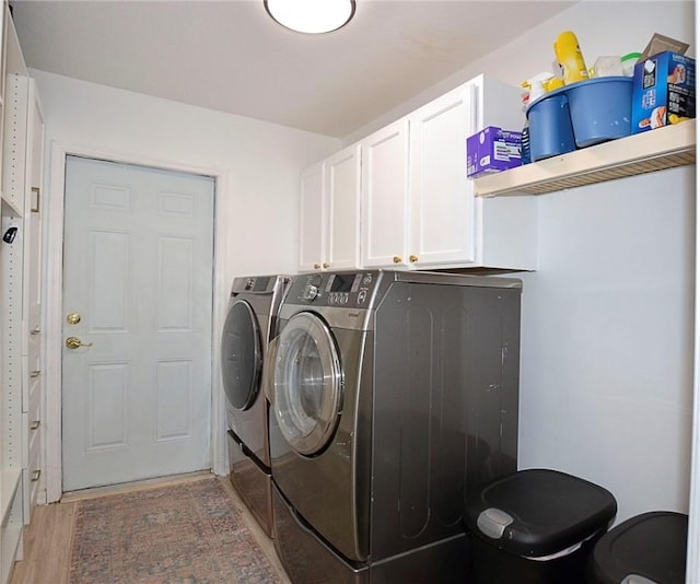 laundry area with cabinets, washing machine and dryer, and light hardwood / wood-style flooring