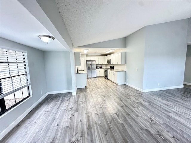 unfurnished living room featuring lofted ceiling, light hardwood / wood-style flooring, and a textured ceiling