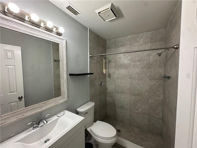 bathroom with vanity, tiled shower, and toilet