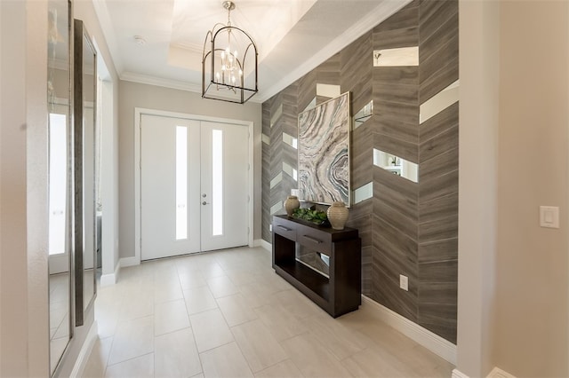 foyer with french doors, a chandelier, and a raised ceiling