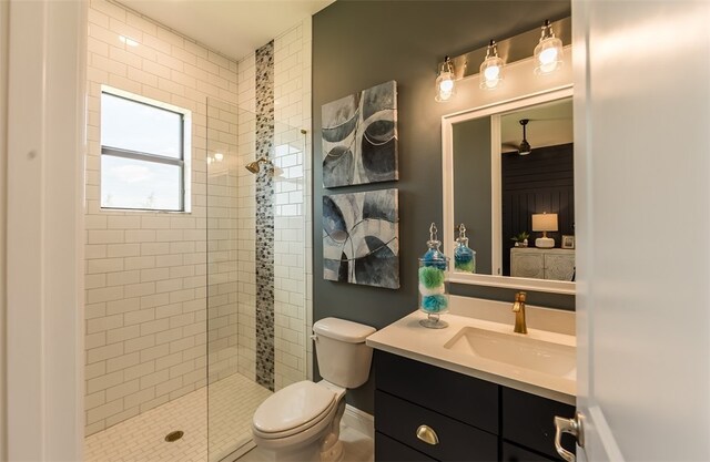 bathroom with a tile shower, vanity, and toilet