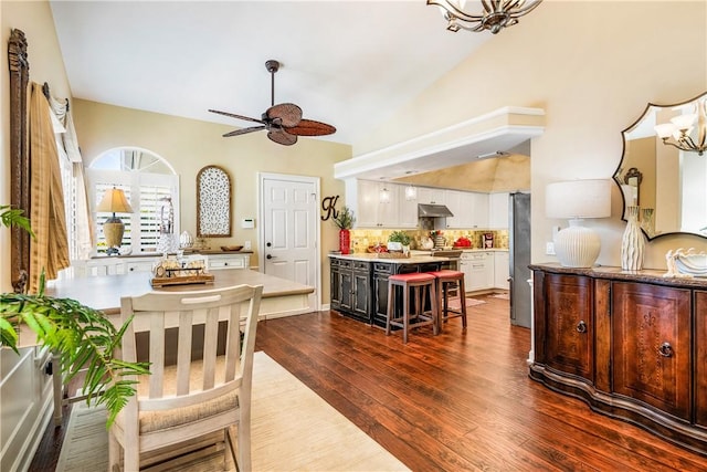 dining area featuring vaulted ceiling, ceiling fan with notable chandelier, and dark hardwood / wood-style flooring