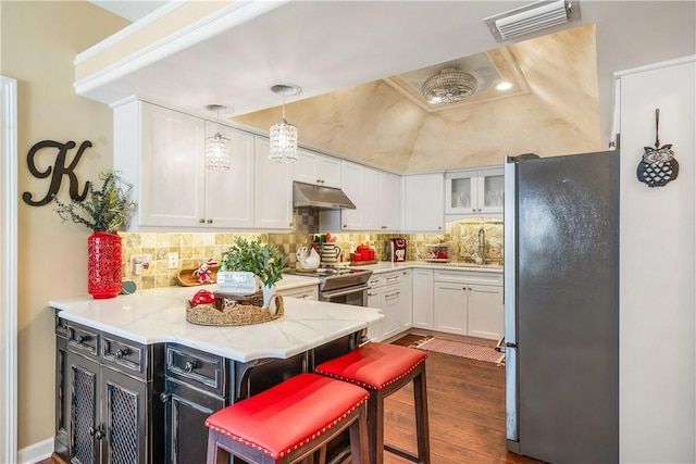 kitchen featuring white cabinetry, hanging light fixtures, appliances with stainless steel finishes, a kitchen breakfast bar, and kitchen peninsula