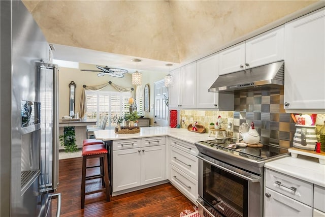 kitchen featuring a breakfast bar, decorative light fixtures, white cabinetry, kitchen peninsula, and stainless steel appliances