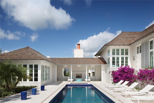 back of house featuring a fireplace, a fenced in pool, and a patio area