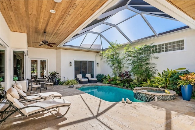 view of pool featuring glass enclosure, french doors, ceiling fan, an in ground hot tub, and a patio area