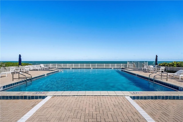 view of swimming pool featuring a water view and a patio