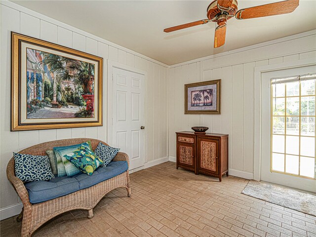 sitting room with wooden walls and ceiling fan